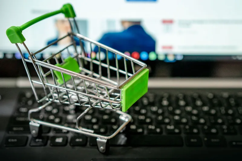 Miniature shopping cart placed on a laptop keyboard, symbolizing online shopping