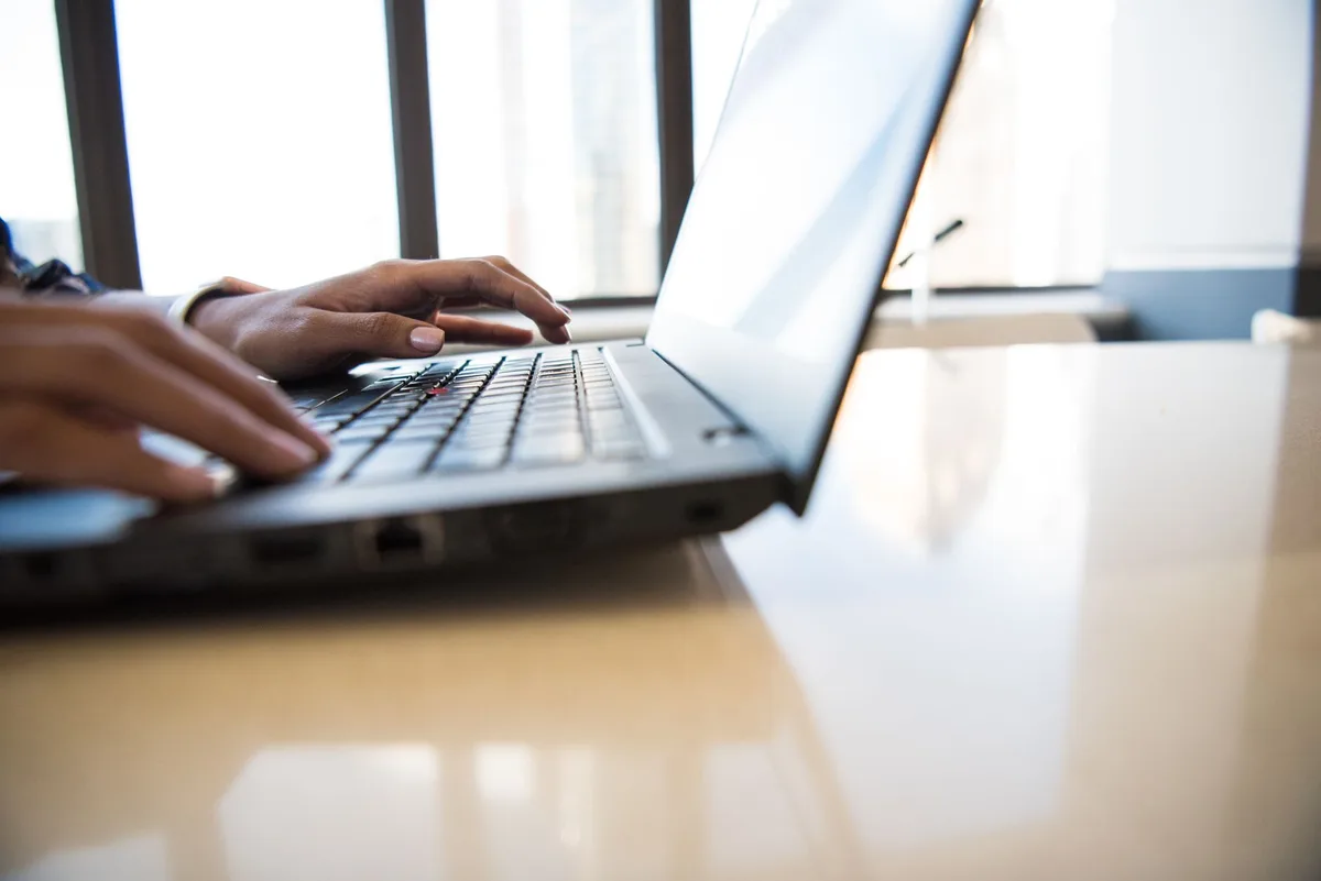Close-up of hands typing on a laptop in a bright office representing ecommerce marketing platform research