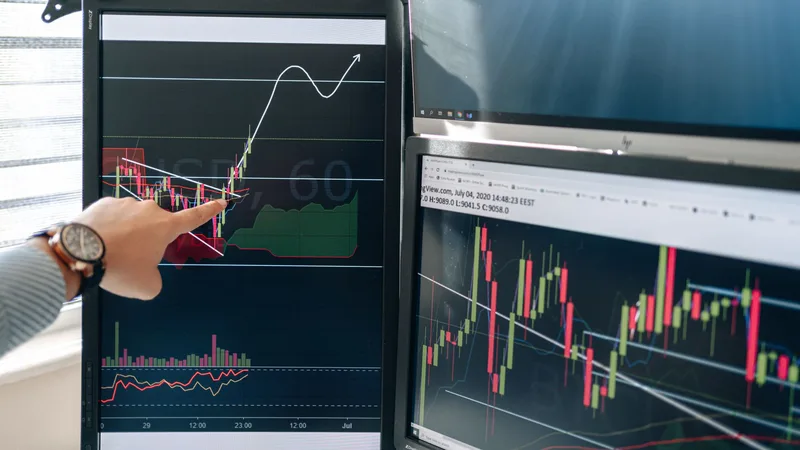 Person pointing at financial graphs on a monitor representing marketing software cost comparison