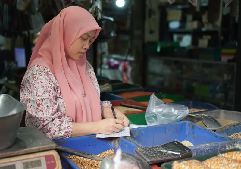 Market vendor calculating sales figures representing the performance tracking process in Lazada Seller Center Ads Manager