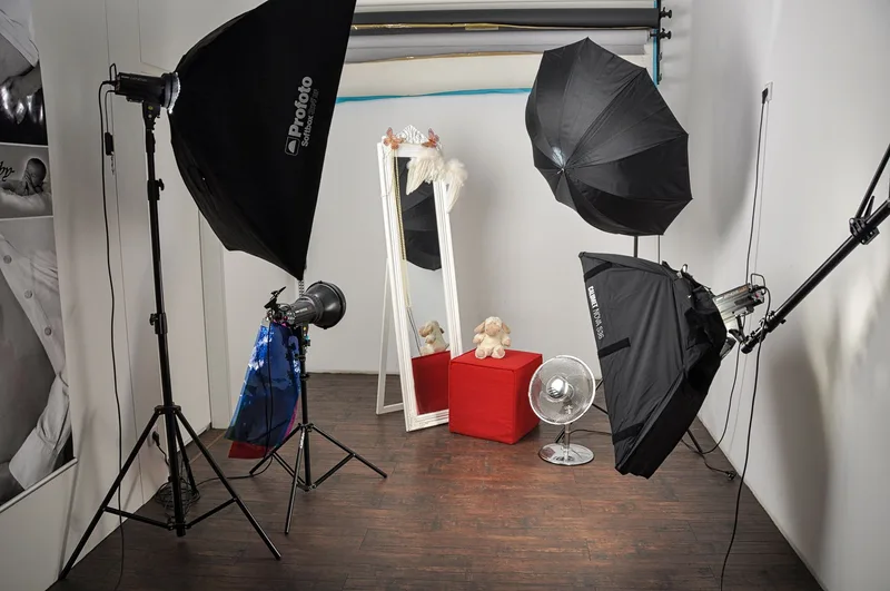 Photography studio lighting setup with softbox and umbrella lights aimed at a small product display